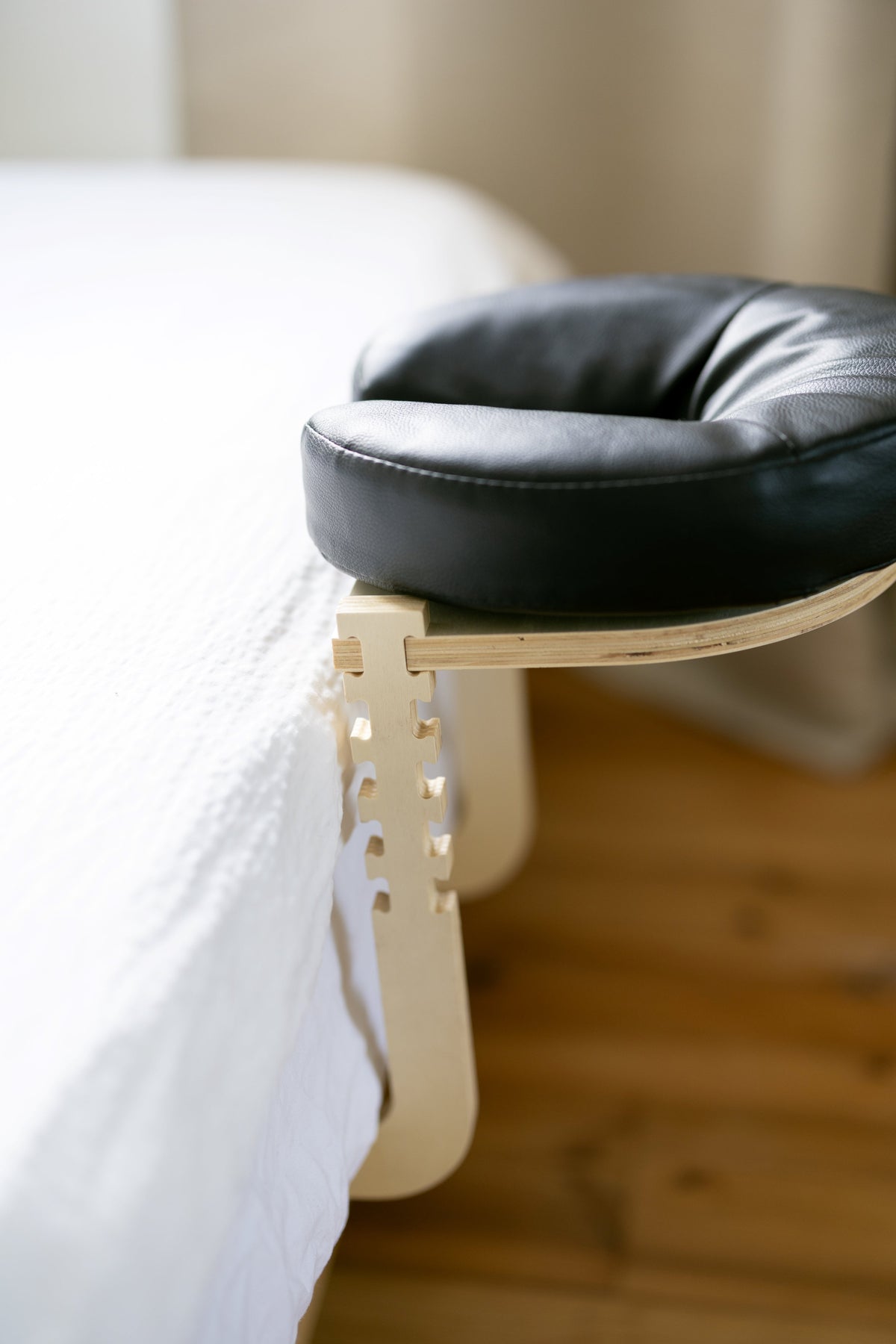 Le coussin de tête noir sur le cadre en bois au bord d'un lit fait