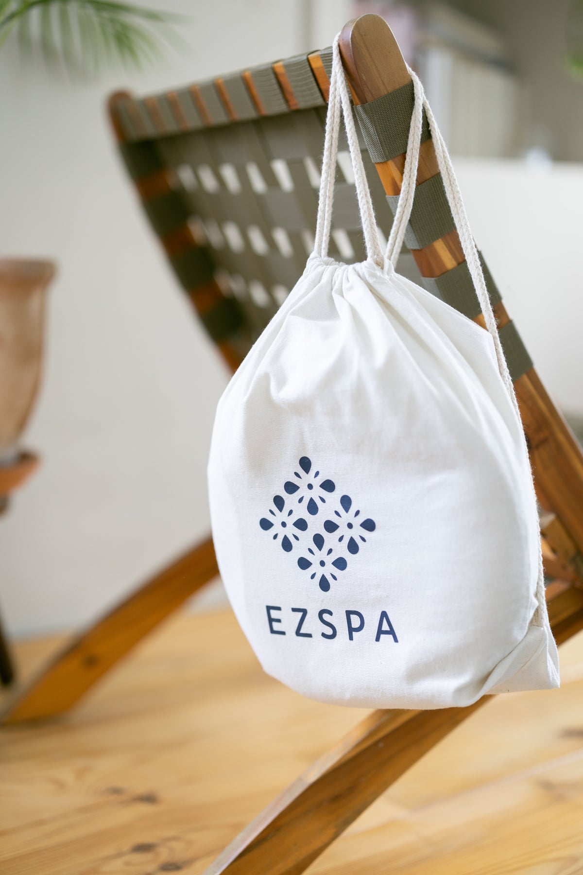 Le sac de transport en coton Ezspa avec le logo, suspendu à une chaise