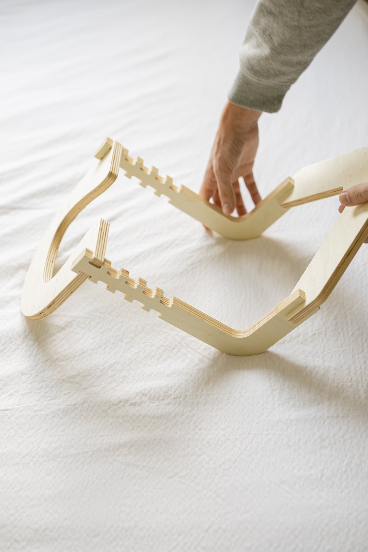 Des mains assemblent le cadre en bois sur un lit fait