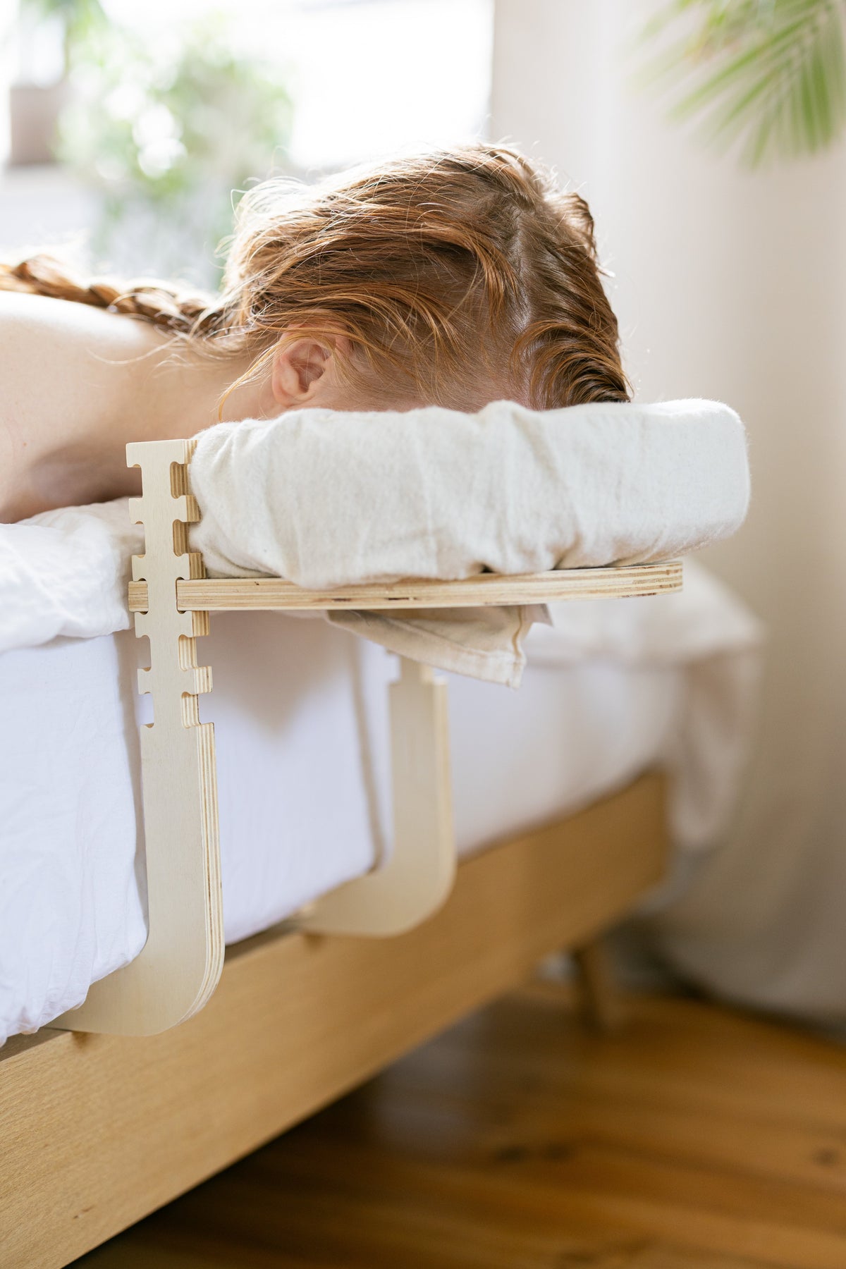Femme aux cheveux tressés, la tête dans l'appui-tête, au bord du lit