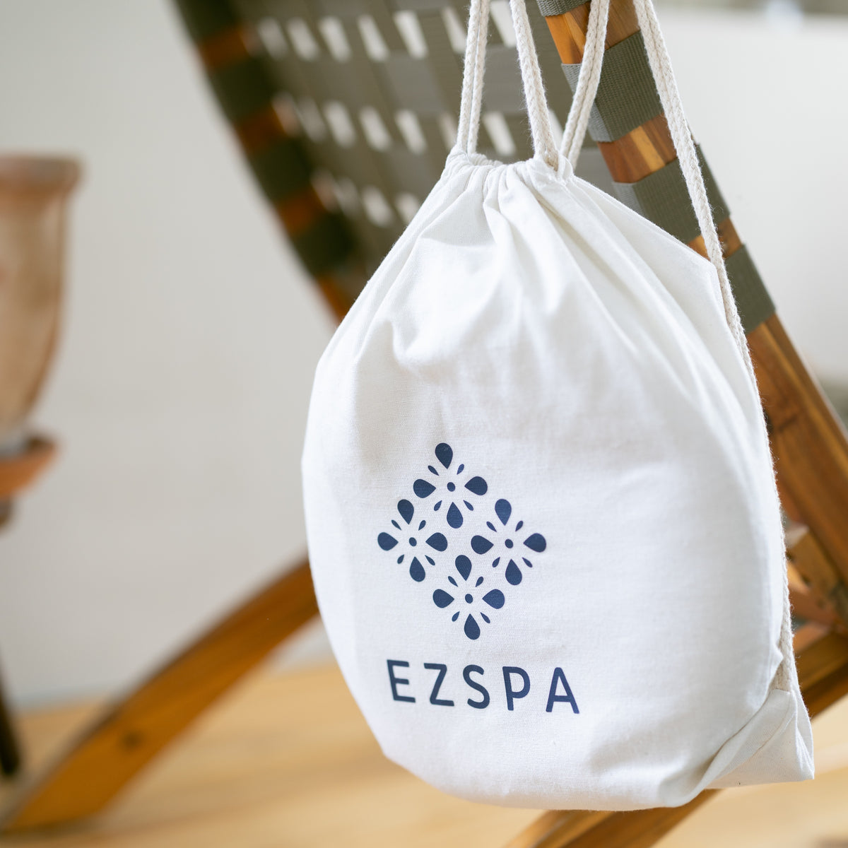Le sac de transport en coton Ezspa avec le logo, suspendu à une chaise