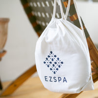 Le sac de transport en coton Ezspa avec le logo, suspendu à une chaise