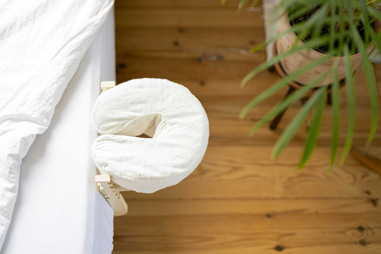 Le Set de massage Ezspa au bord d'un lit fait, sur un parquet en bois